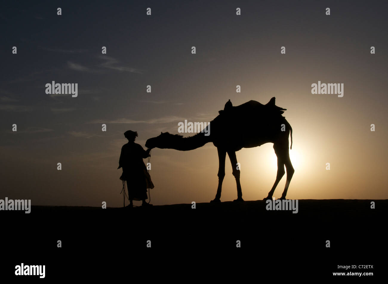 Silhouette Mensch und Kamel bei Sonnenuntergang Sam Dünen Desert National Park westlichen Rajasthan Indien Stockfoto