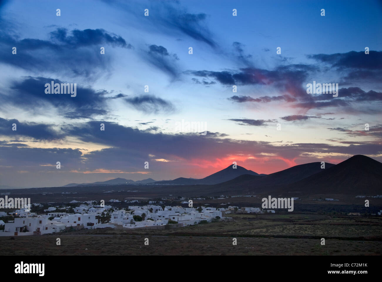TAHICHE LANZAROTE feurig Rote Sonne hinter Vulkan mit Dorf La Asomada im Vordergrund Lanzarote Kanarische Inseln Spanien Stockfoto