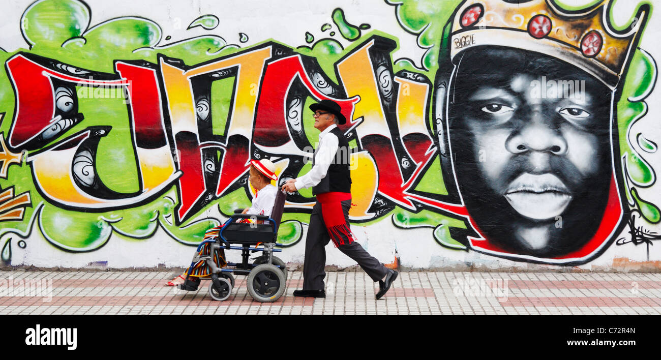 Paar in Tracht auf Weg zur Fiesta mit Graffiti im Hintergrund. Las Palmas, Gran Canaria, Kanarische Inseln, Spanien Stockfoto