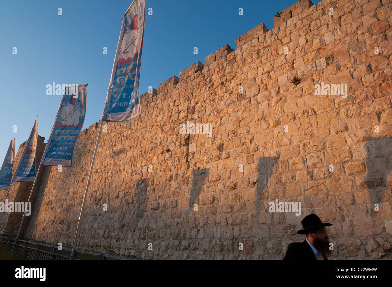 Stadtmauer bei Sonnenuntergang mit Fahnen und orthodoxer Jude. Jaffa-Tor. Altstadt von Jerusalem. Israel Stockfoto