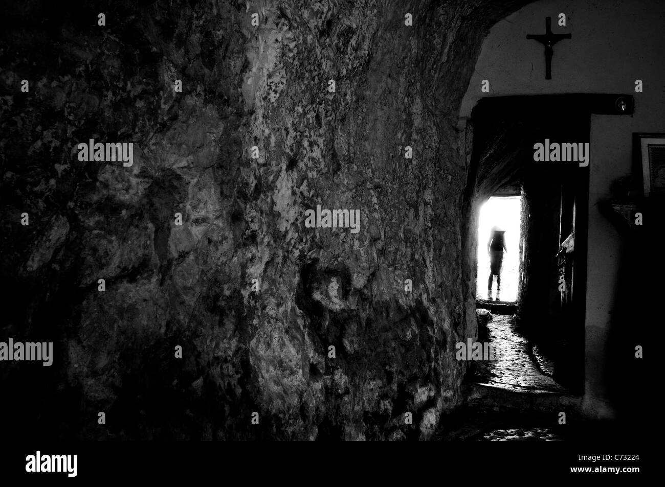 In den Felsenraum gehauene Einsiedelei mit Kruzifix und Hexensilhouette Stockfoto