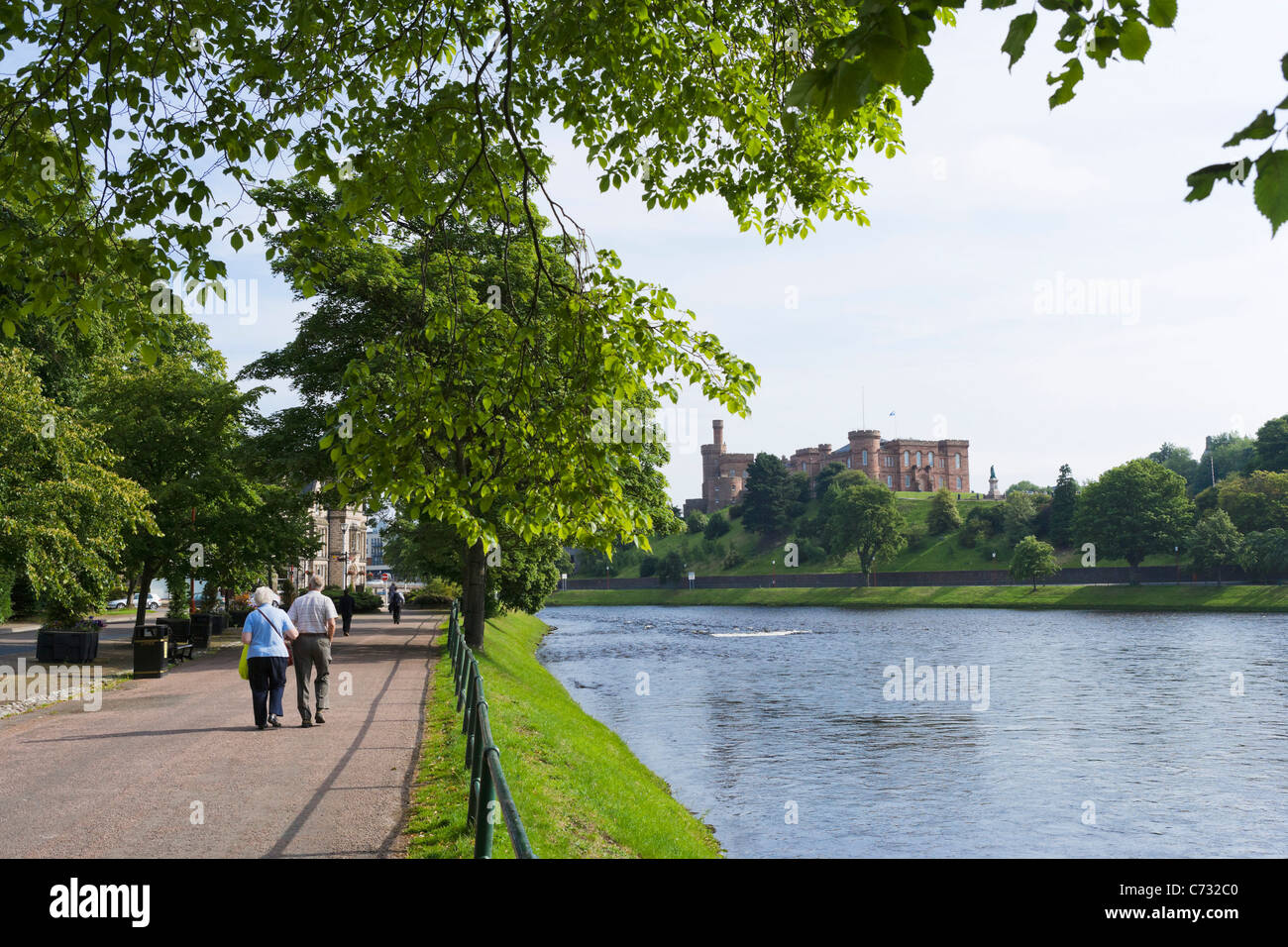 Älteres Ehepaar zu Fuß entlang der Pfad am Ufer des River Ness mit der Burg in Ferne, Inverness, Highland, Schottland, Großbritannien Stockfoto