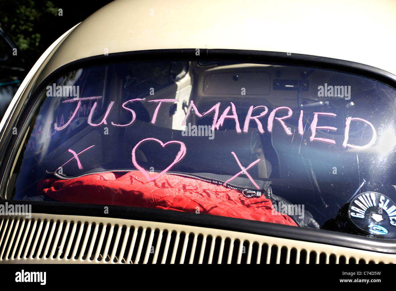 "Just Married" auf der Heckscheibe eines Autos in rotem Lippenstift gezeichnet. Stockfoto