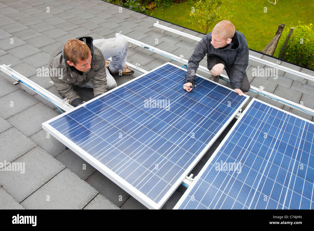 Arbeitnehmer, die Installation von solar-Elektro-Panels auf einem Hausdach in Ambleside, Großbritannien. Stockfoto
