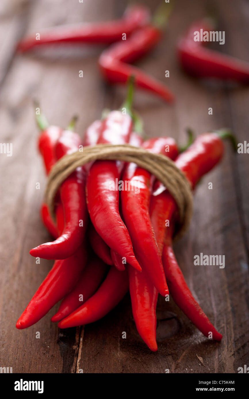 Rote Chilischoten mit einem Seil auf Holz gefesselt Stockfoto