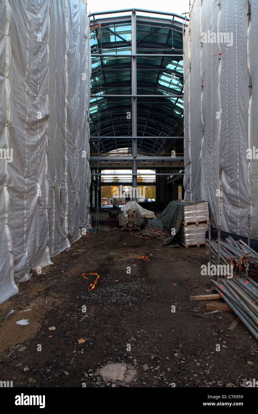 Hängende planen und Glas- und Stahlkonstruktionen auf einer Shopping-Mall-Baustelle. Stockfoto