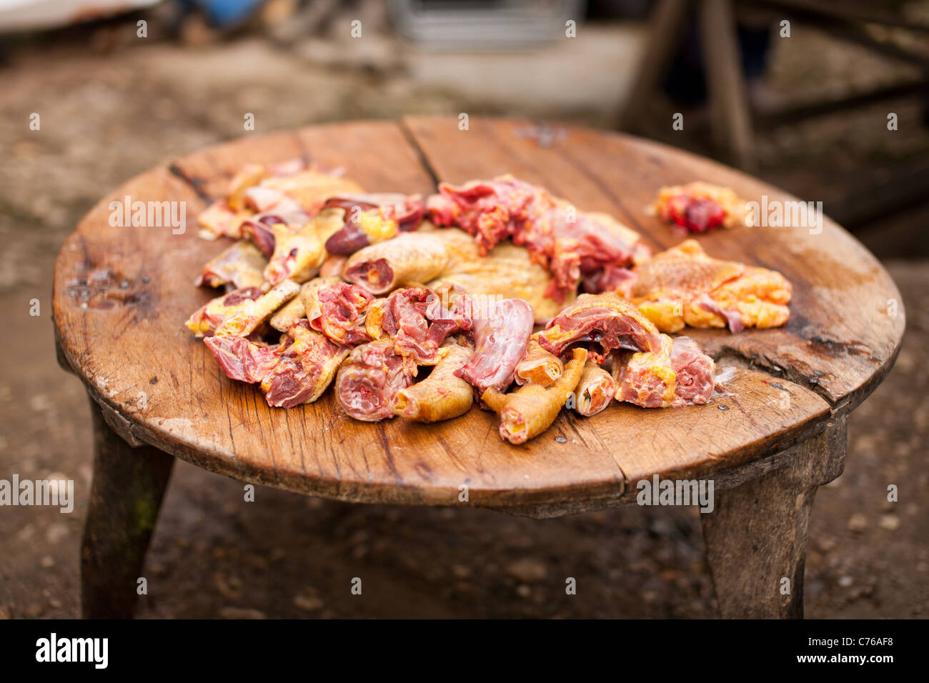 Rohem Hühnerfleisch auf einem abgenutzten Vintage runden Holztisch im freien Stockfoto