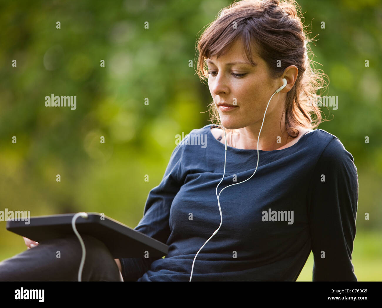 UK, London, junge Frau im Park sitzen und mit digital-Tablette Stockfoto