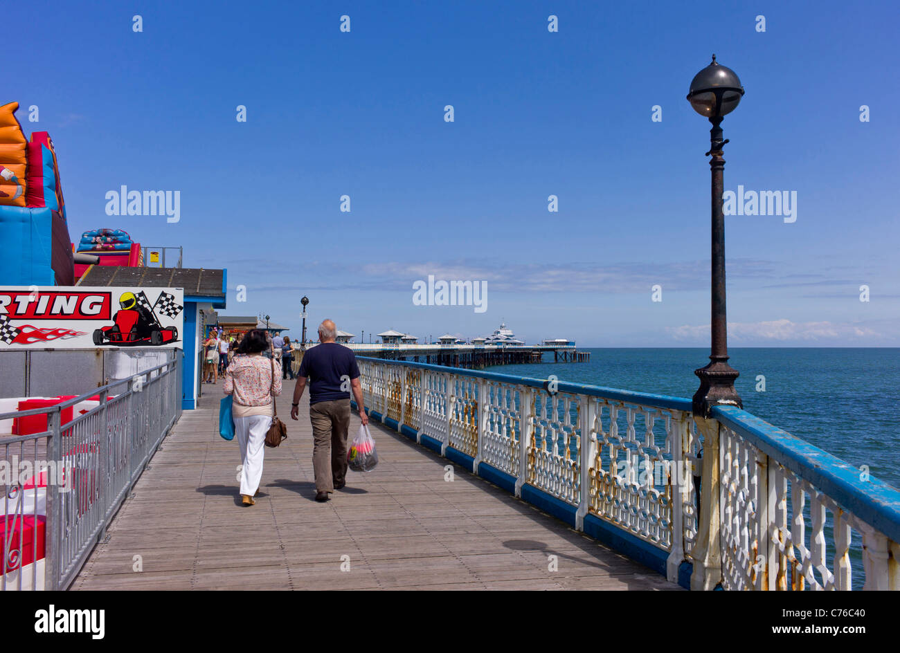 Erwachsene männliche und weibliche Spaziergang Llandudno Pier letzten Vergnügungen, mit Blick auf das Ende des Piers, Ruhe, Meer und blauer Himmel Stockfoto