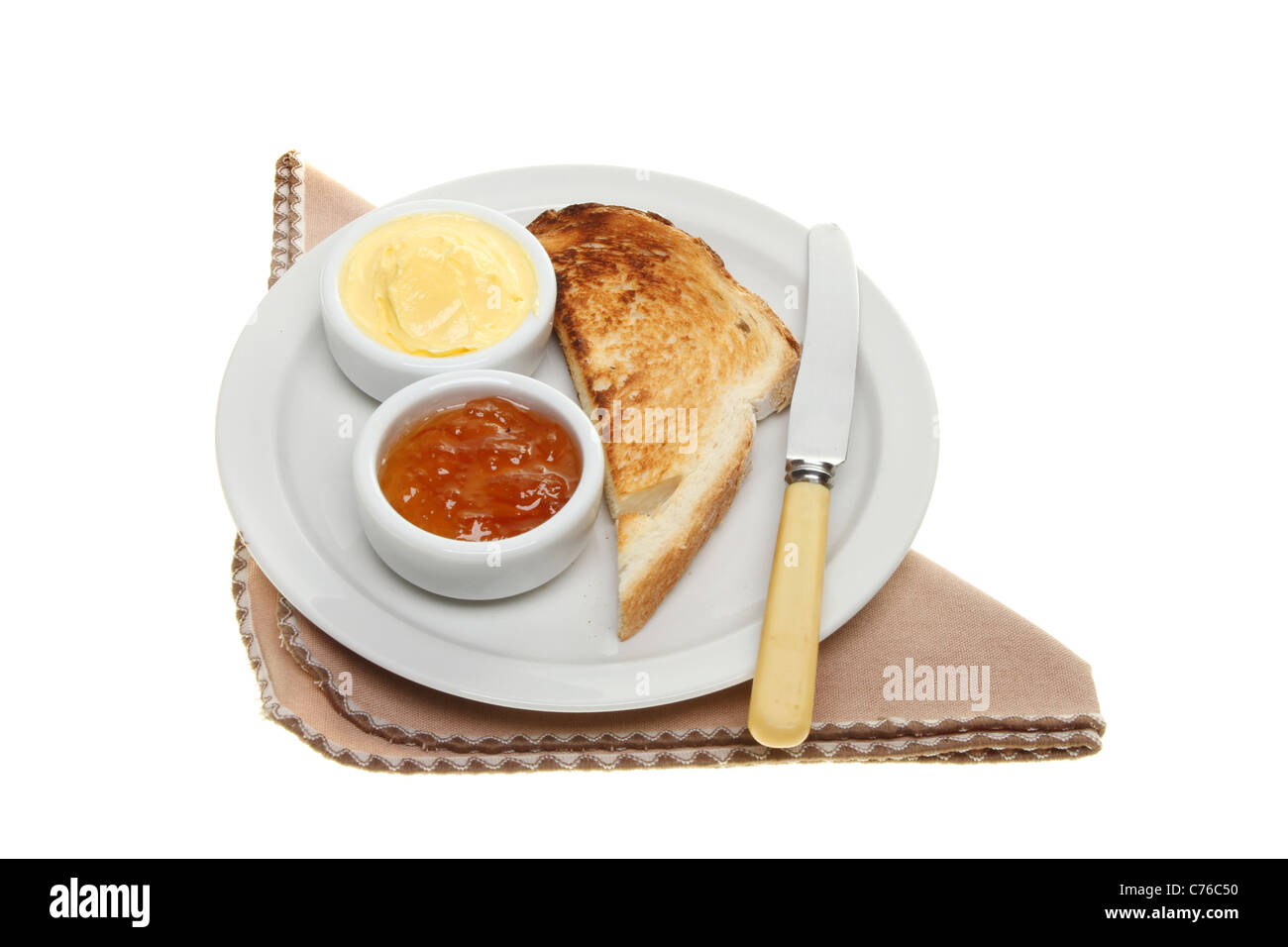 Toast, Butter und Marmelade auf einem Teller mit Messer und isoliert gegen weiße Serviette Stockfoto