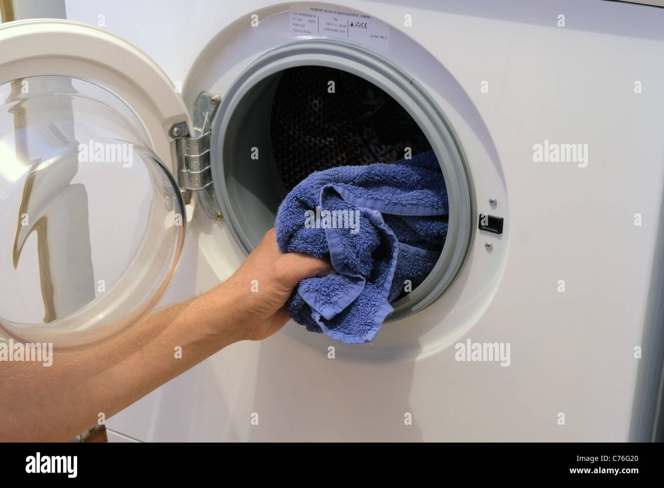 Kaukasischen Männchen be- oder Entladen einer elektrischen Bosch Waschmaschine, UK-Modell veröffentlicht Stockfoto