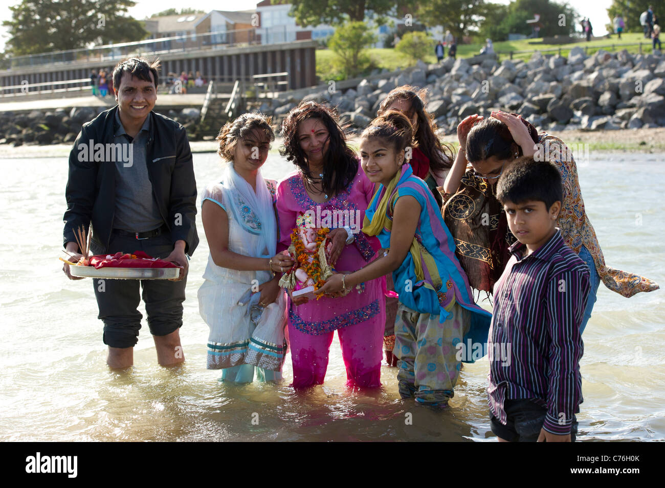 Eine hinduistische Familie Stand im Meer mit einer Statue von Ganesh, die im Rahmen des Ganesh Festivals eingetaucht ist. Fotografie: Simon Ford Stockfoto