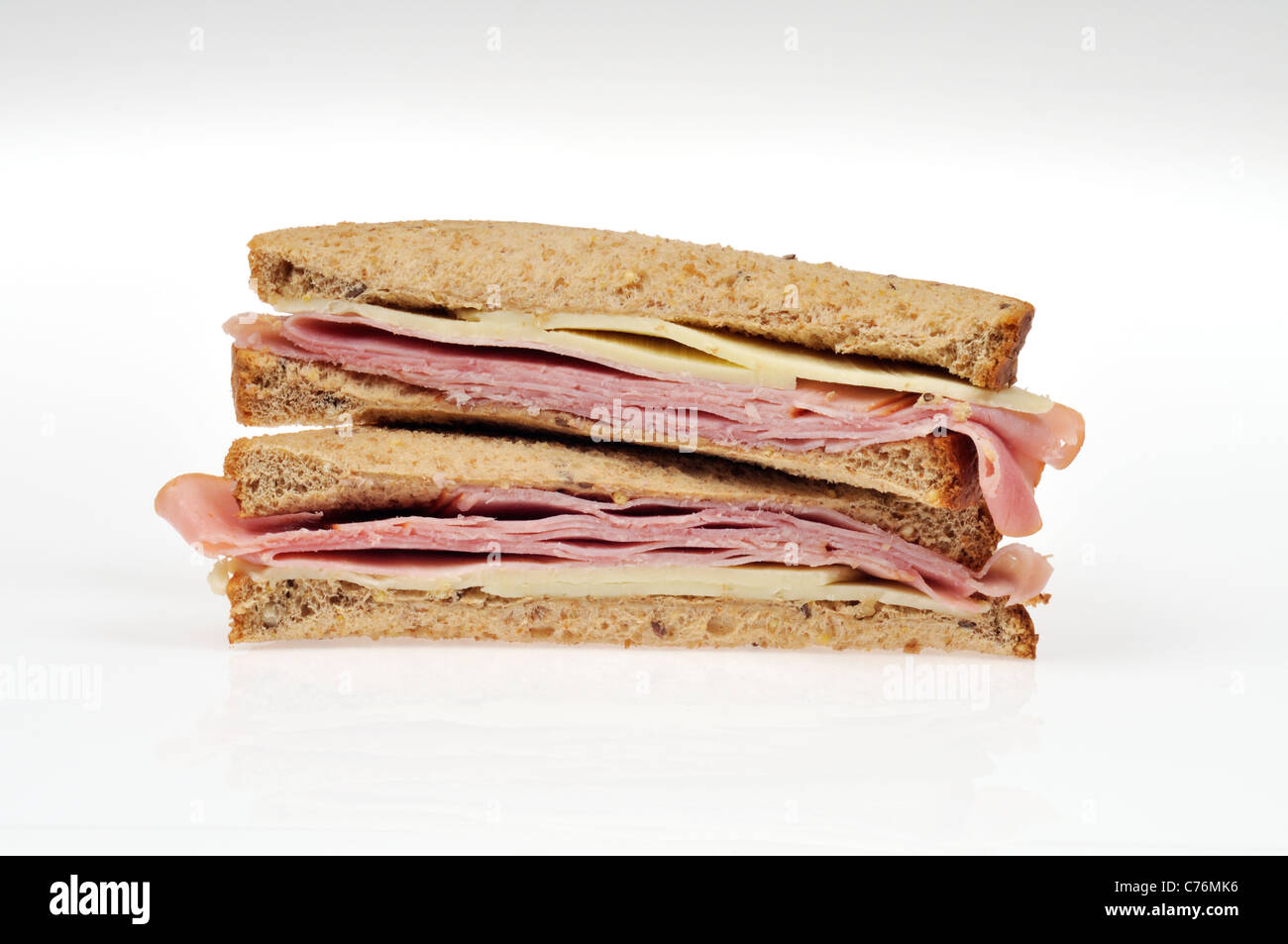 Hälften der Schinken und Käse Sandwich auf ganze Mahlzeit Brot mit Salat gestapelt auf weißem Hintergrund, isoliert. Stockfoto