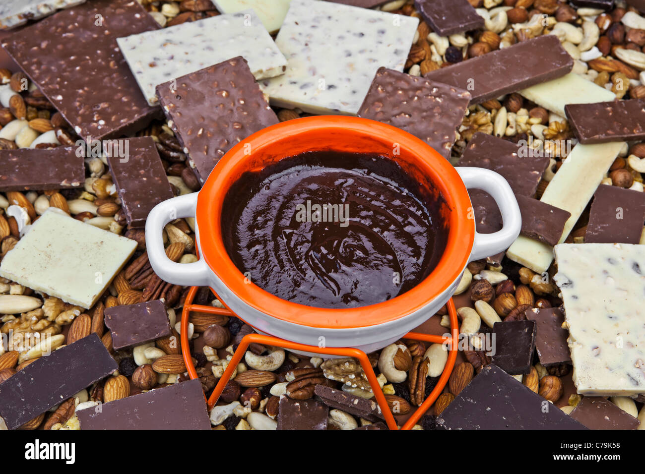 geschmolzene Schokolade in einem Fonduetopf in der Mitte eines Stapels Schokoladenstücke Stockfoto