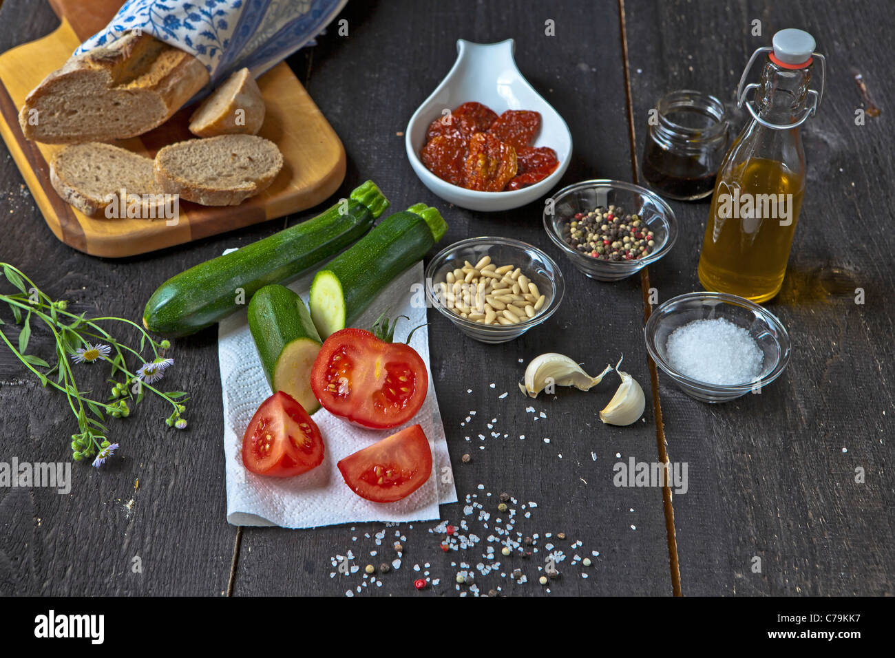 frische Zutaten wie Zucchini, Tomaten, getrocknete Tomaten, Pinienkerne, Pfeffer, Salz, Olivenöl und Balsamico-Essig für einen Salat Stockfoto