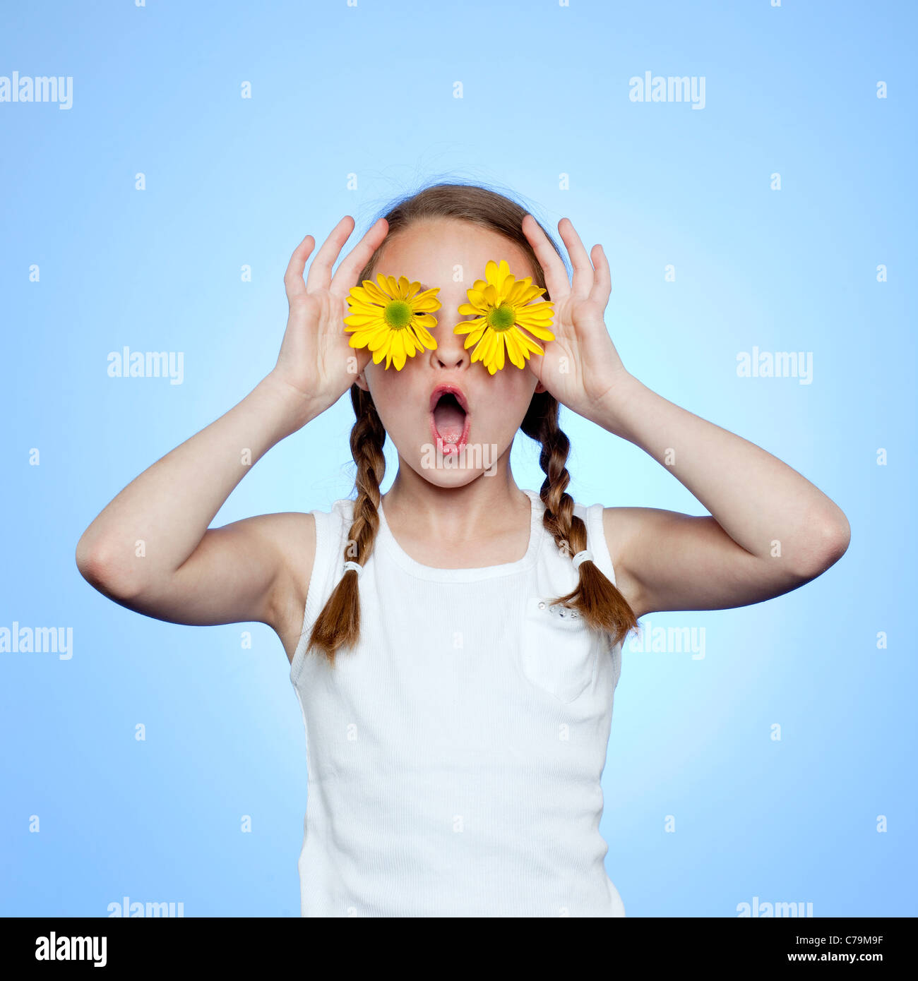 Studio-Porträt von Mädchen (10-11) Abschirmung Augen von zwei gelben Blüten Stockfoto