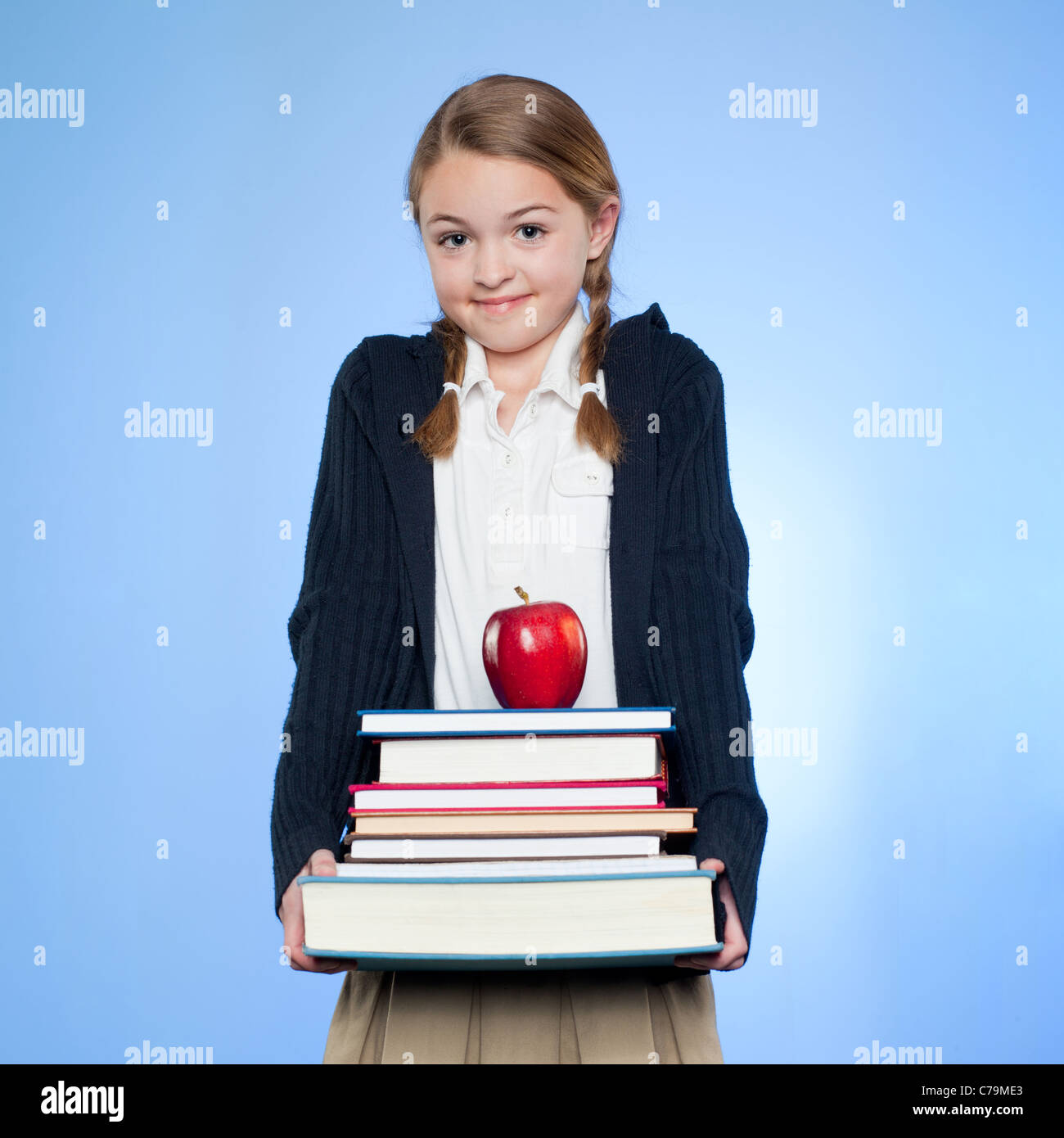Studio-Porträt von Mädchen (10-11) Holding Stapel von Büchern und Apfel Stockfoto