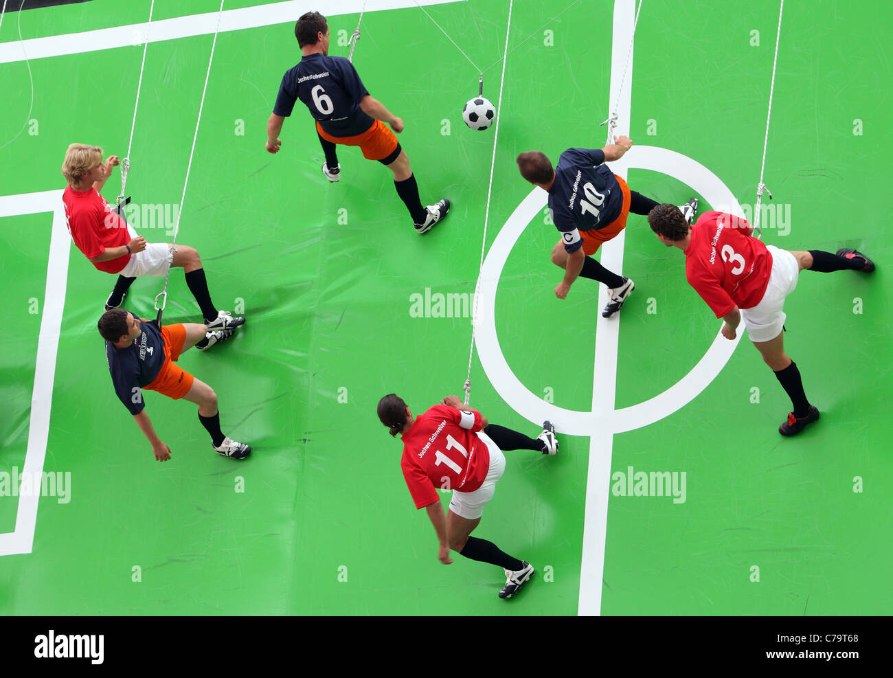 Fußball-Spieler hängen in Seilen, Fußball spielen auf einem vertikalen Bereich, München, Deutschland Stockfoto