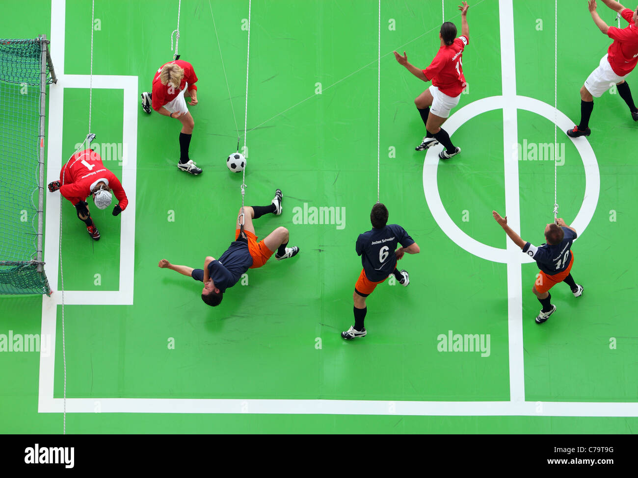 Fußball-Spieler hängen in Seilen, Fußball spielen auf einem vertikalen Bereich, München, Deutschland Stockfoto