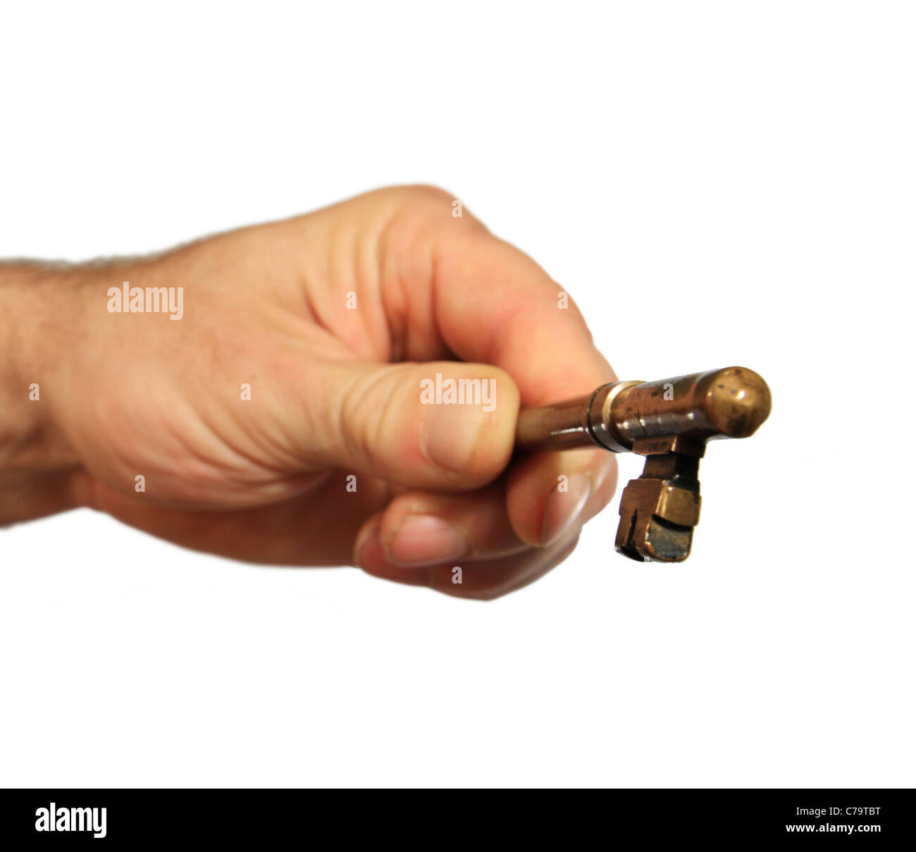 eine isolierte Mannes Hand hält einen antiken Messing Schlüssel in Richtung des Betrachters mit selektiven Fokus auf die Taste Stockfoto