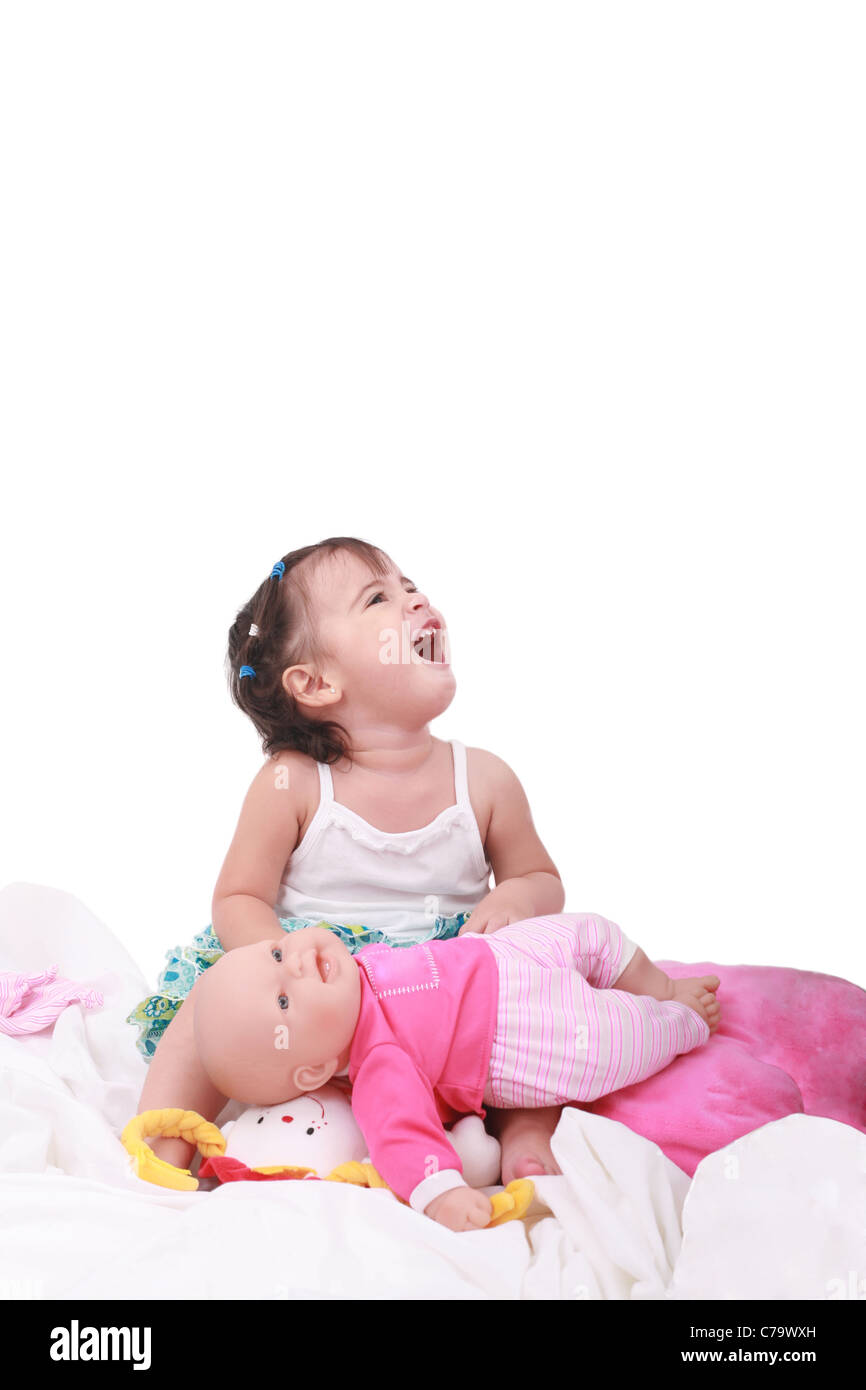 glückliches kleines Mädchen sitzen im Bett mit ihren Puppen Stockfoto