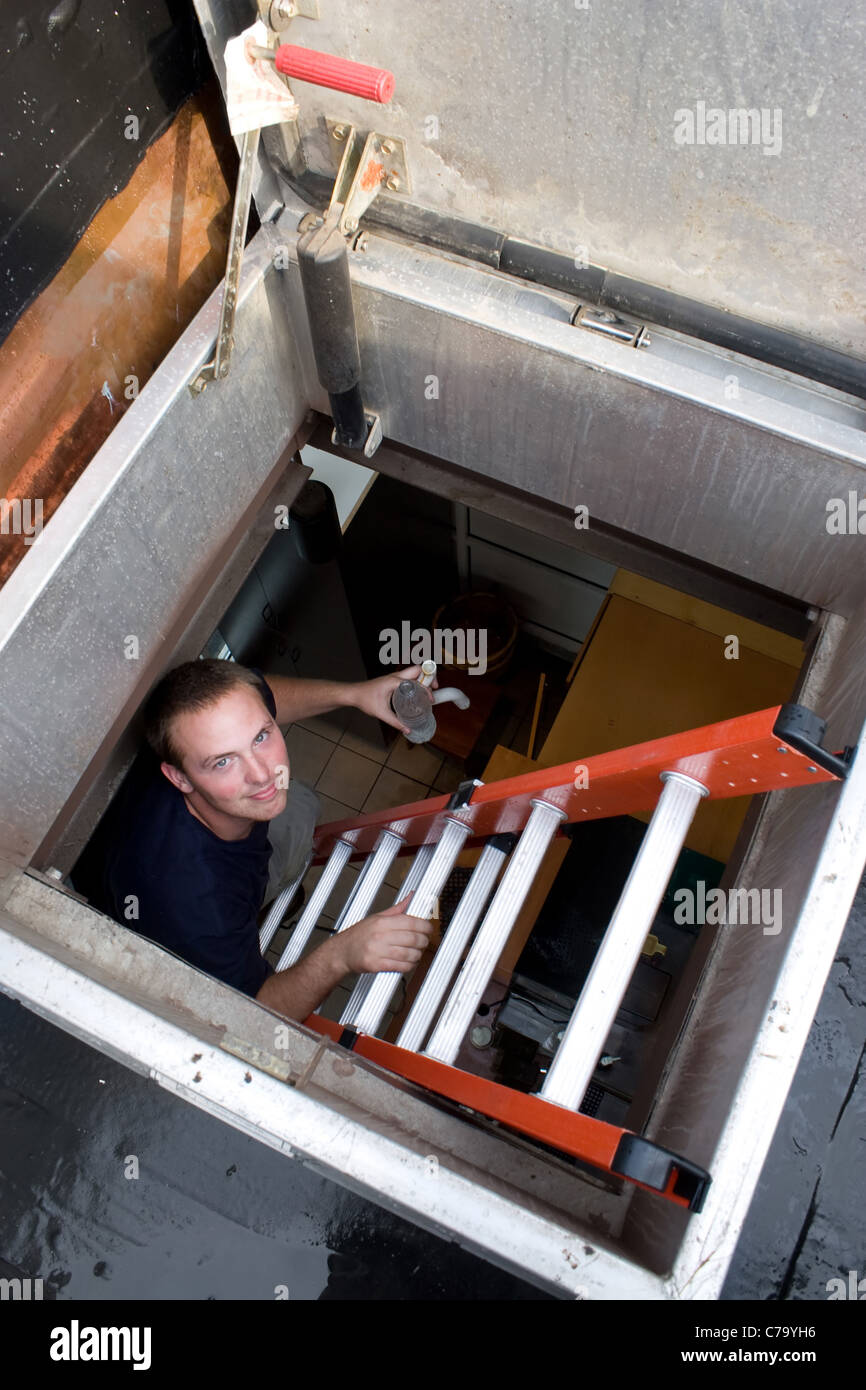 Eine junge HLK-Techniker klettert eine Leiter auf dem Dach. Stockfoto