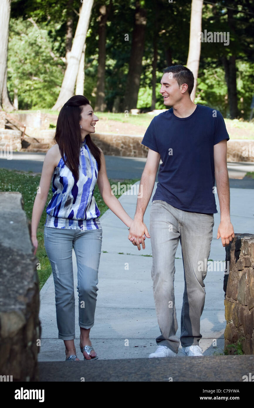 Ein glückliches junges Paar in ihrer Mitte der zwanziger Jahre Lächeln einander bei einem Spaziergang durch den Park. Stockfoto