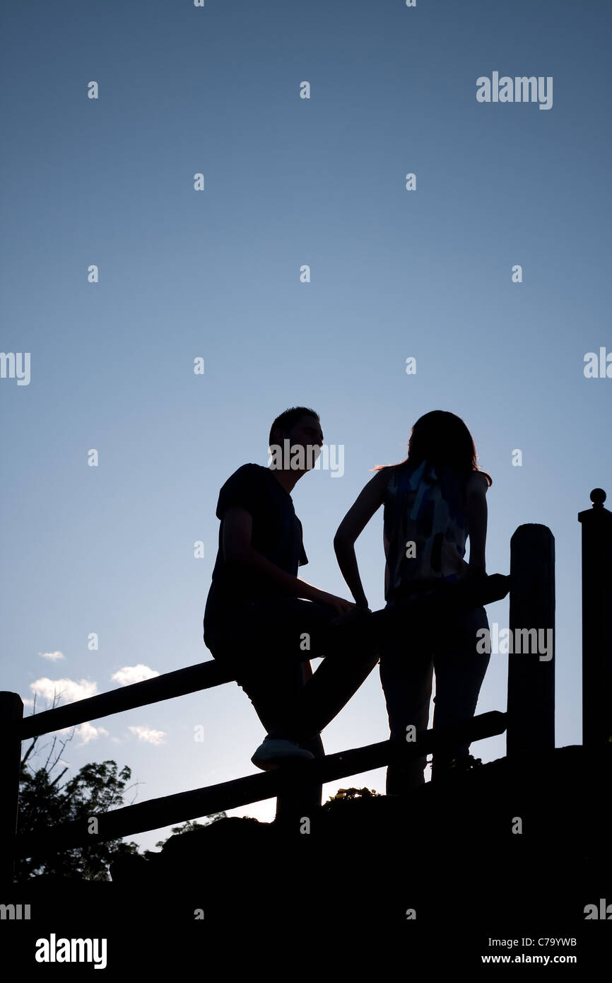 Silhouette eines jungen Paares hängen zusammen im Freien durch ein altes Land-Zaun in den frühen Abendstunden. Stockfoto