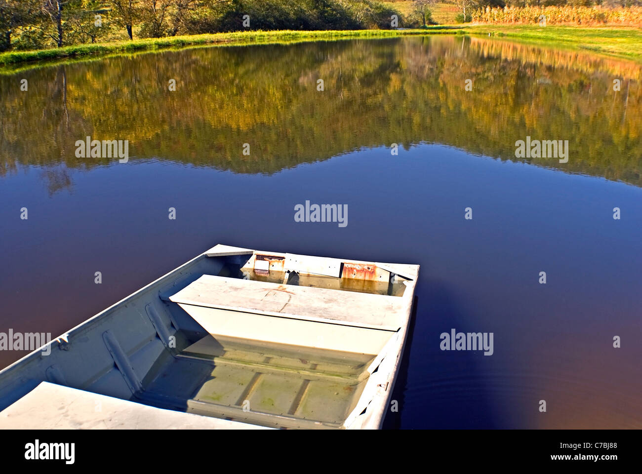 Eine verlassene Boot links am Ufer eines Sees. Berg-Spiegelungen im Wasser. Stockfoto