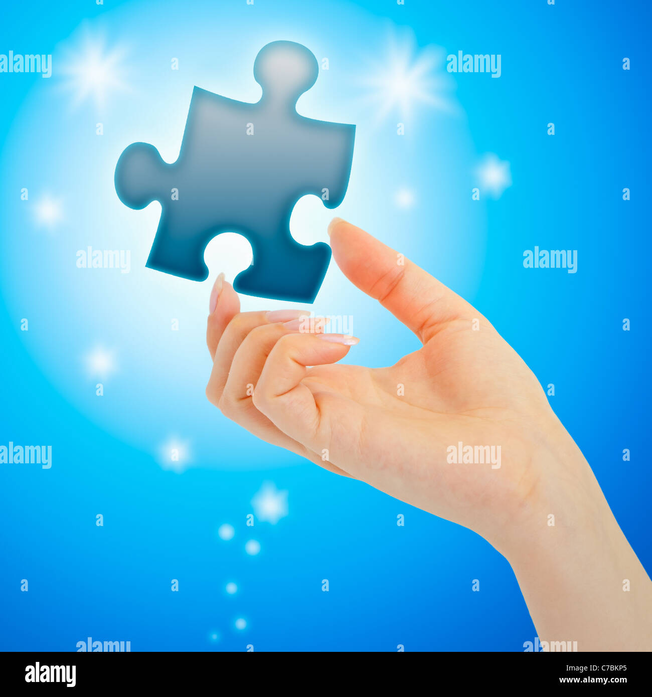 Weibische Hand mit einem blau leuchtenden Teil des Puzzles auf blauem Hintergrund Stockfoto