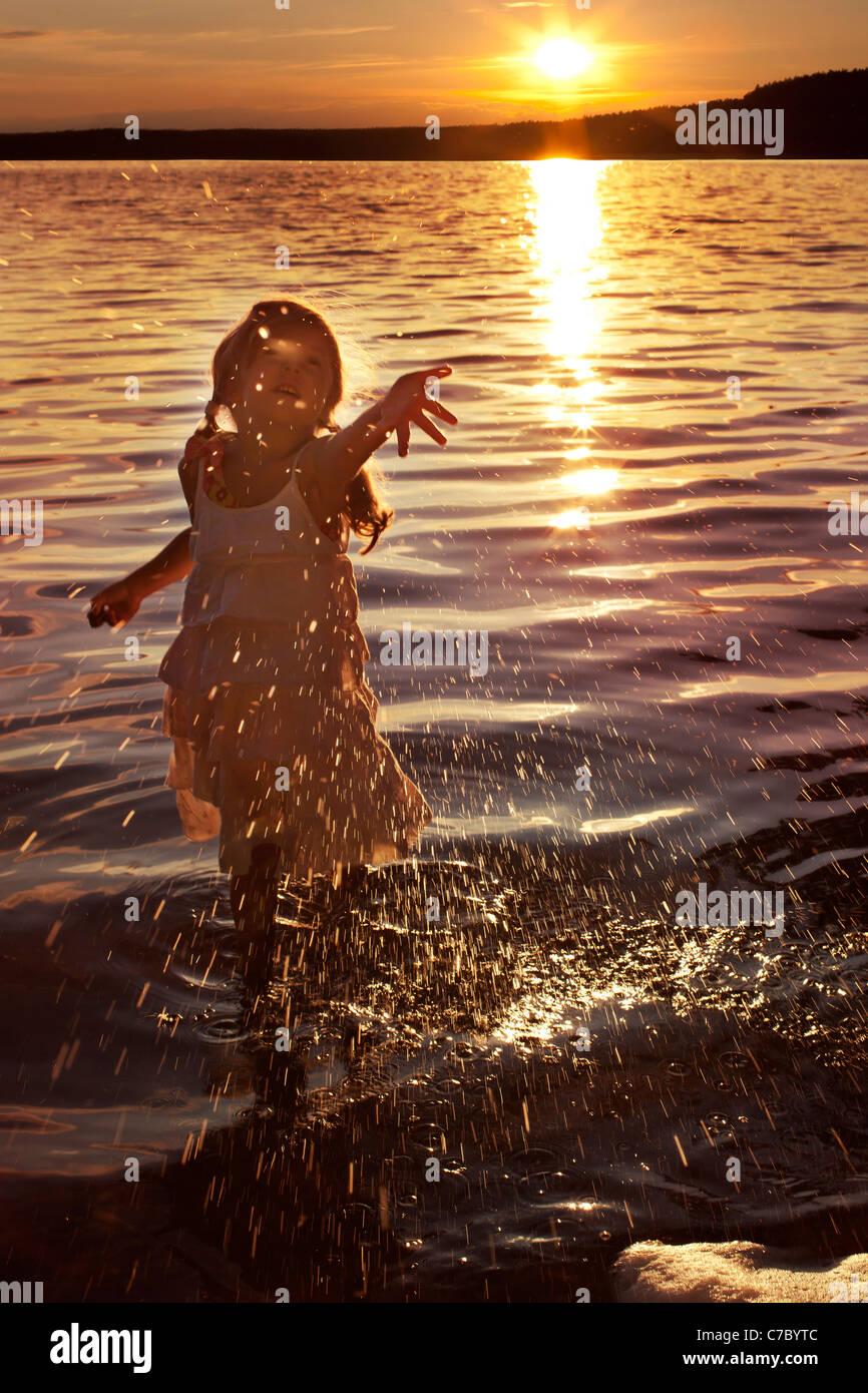 glückliche Mädchen spritzt sich Wasser in den See Stockfoto
