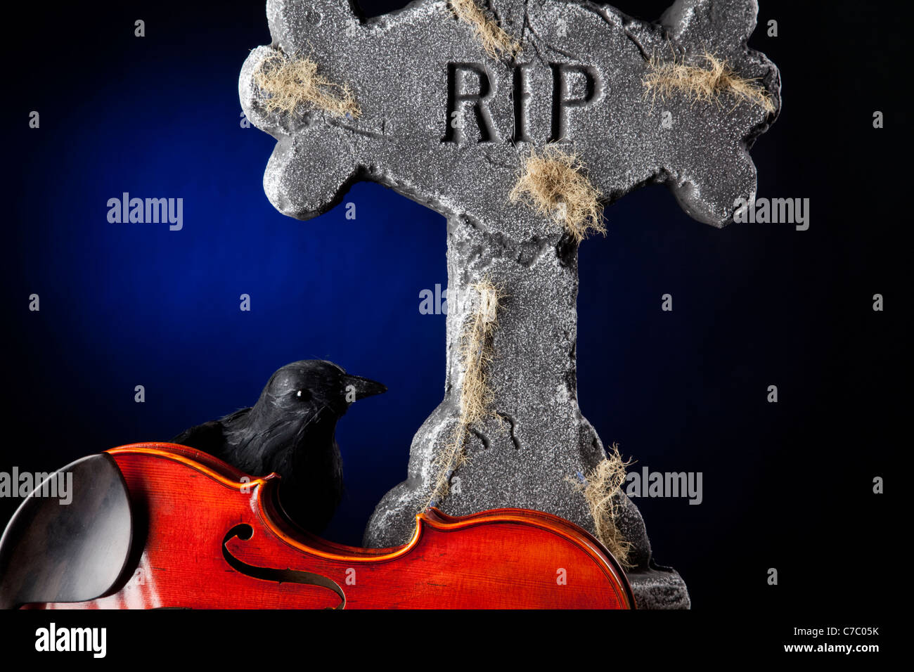 Ein Halloween Violine Viola mit einer Amsel Krähe und Grabstein Hintergrund dunkel blaue Scheinwerfer. Stockfoto