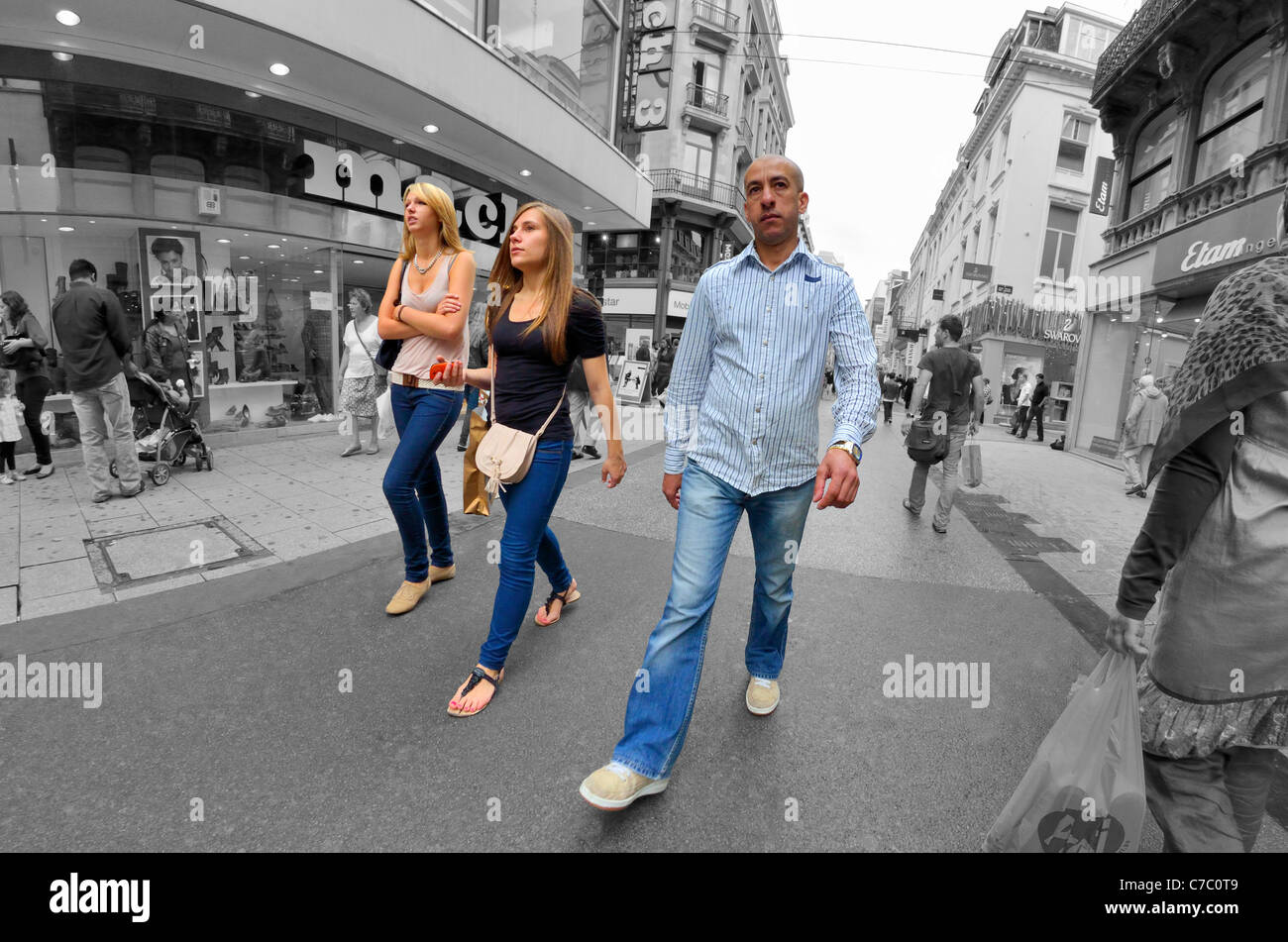 Brüssel, Belgien. Drei Menschen auf Einkaufsstraße - Hintergrund in schwarz / weiß Stockfoto