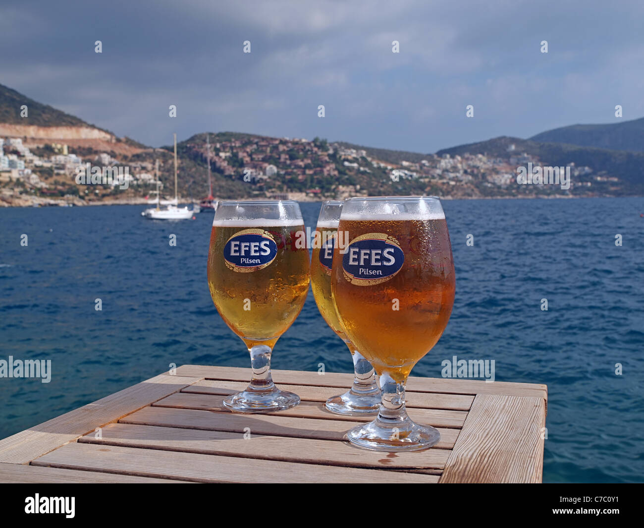 Eine Tabelle mit drei Efes Bier mit Blick auf den Hafen von Kalkan in der Türkei Stockfoto