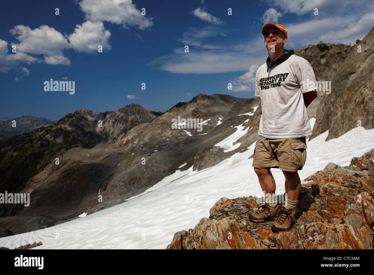 Backpacker stehend auf felsigen Felsvorsprung mit Blick auf Gletscher, Bailey Bereich durchqueren, Olympic Mountains, Washington Stockfoto