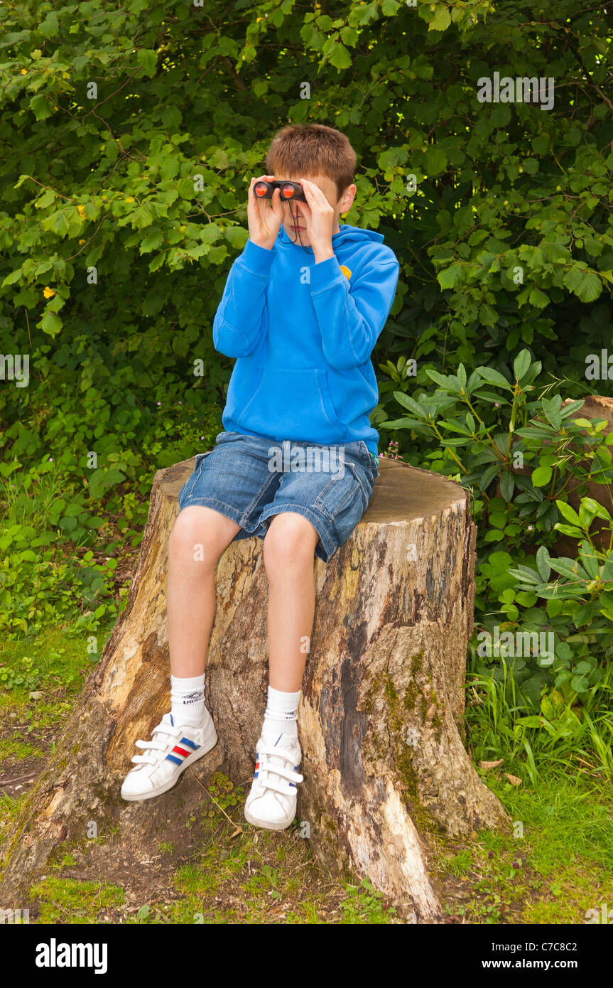 Ein elf Jahre alter Junge Vogelbeobachtung mit dem Fernglas in Fairhaven Garten, Wald und Wasser im Süden Walsham, Norfolk, Großbritannien Stockfoto