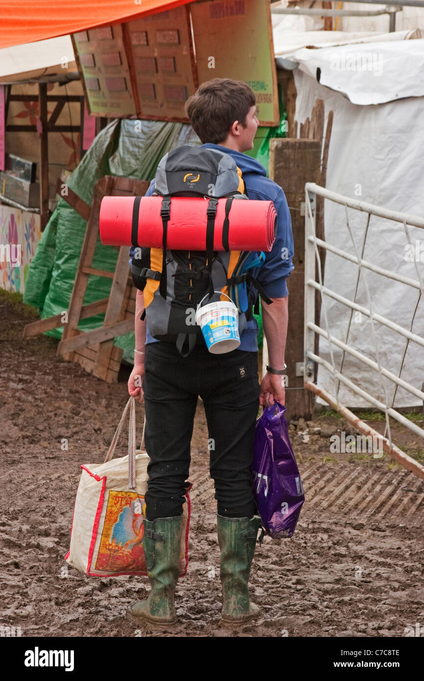 Ein Zecher kommt bei Glastonbury in ihre Gummistiefel mit Campingausrüstung Stockfoto