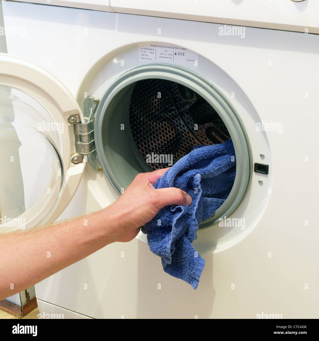 Kaukasischen Männchen be- oder Entladen einer elektrischen Bosch Waschmaschine, UK-Modell veröffentlicht Stockfoto