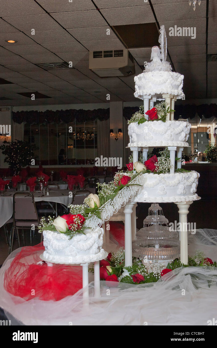 Großer, mehrstufiger Kuchen mit beleuchtetem Brunnen unter der Decke und Braut- und Besenfiguren, die während des Empfangs in den USA auf dem Tisch ausgestellt werden Stockfoto