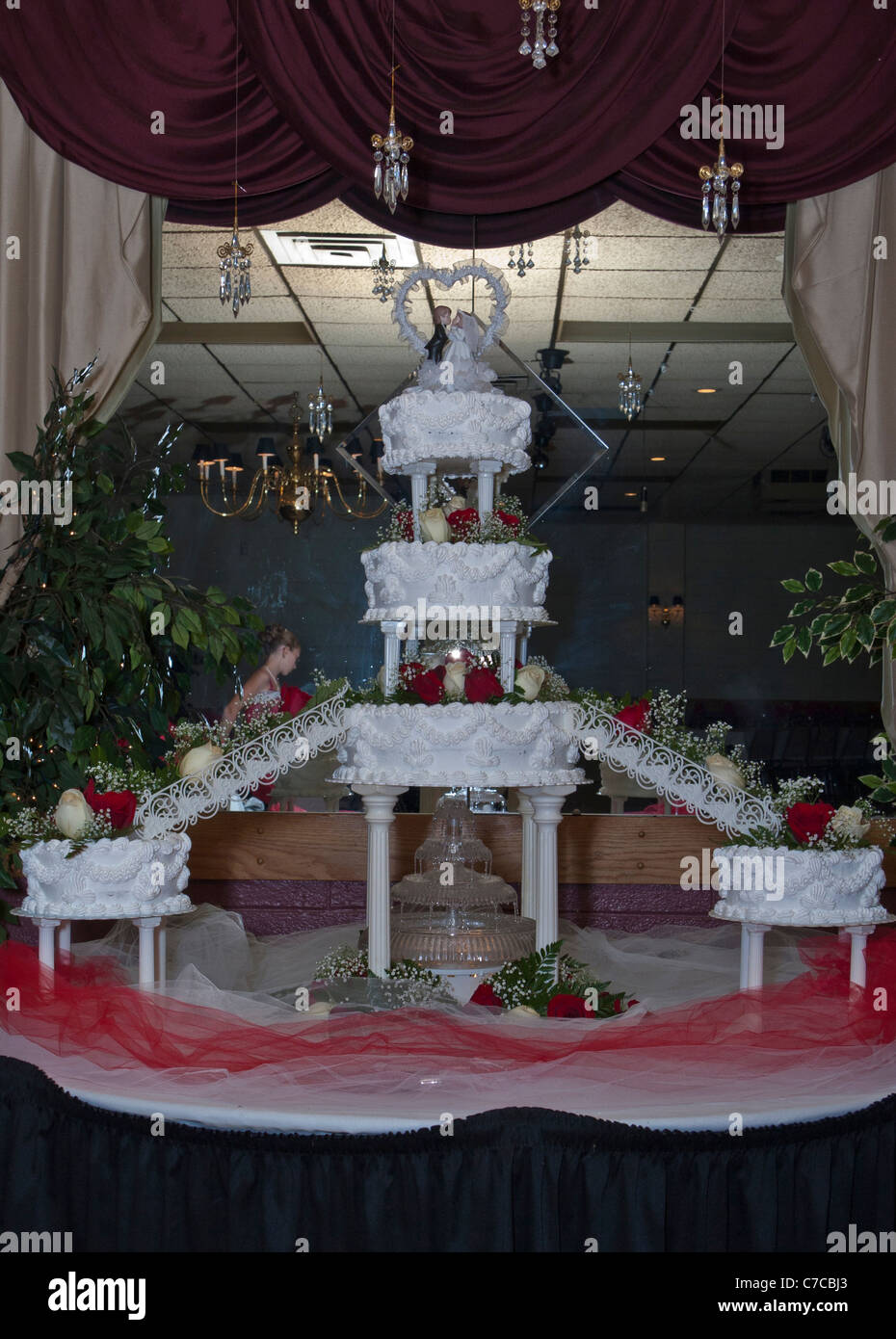 Großer, mehrstufiger Kuchen mit beleuchtetem Brunnen unter der Decke und Braut- und Besenfiguren auf dem Tisch in den USA Stockfoto
