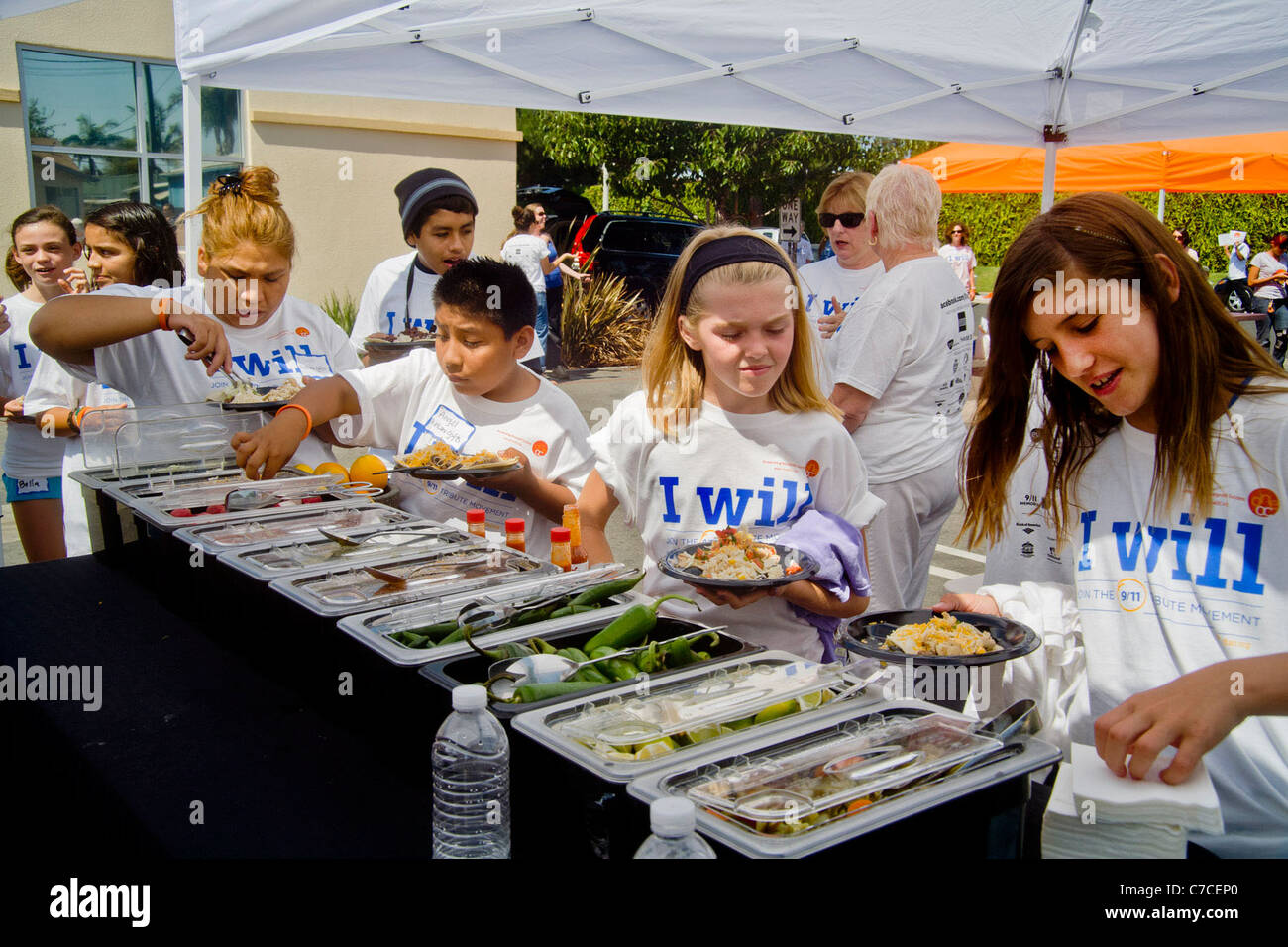 Jungen Erwachsenen Freiwilligen im Logo T-shirts Mittagessen auf mexikanisches Essen auf ein Gemeinschaftsprojekt Verschönerung in Santa Ana, Kalifornien. Stockfoto
