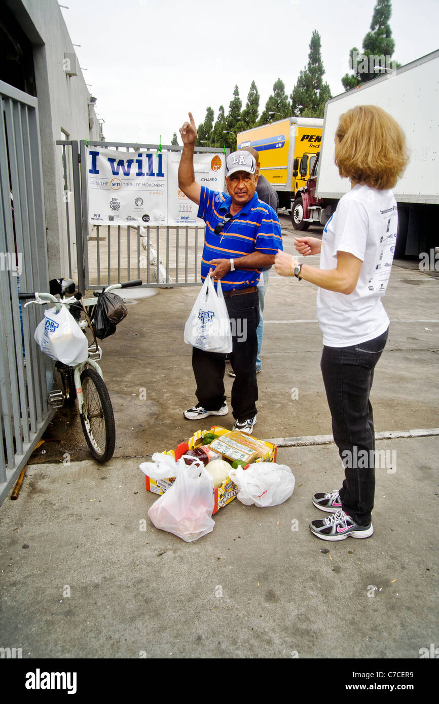 Ein afrikanischer amerikanischer Mann spricht mit freiwilliger während Verpackung gespendet Essen bei einer Charity-Verteilung in Santa Ana, Kalifornien. Stockfoto