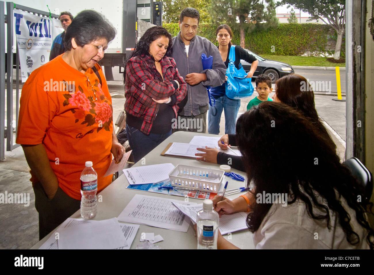 Hispanische Menschen unterschiedlichen Alters registrieren Sie sich kostenlos Lebensmittel an eine Wohltätigkeitsorganisation Lager Distribution in Santa Ana, Kalifornien. Stockfoto