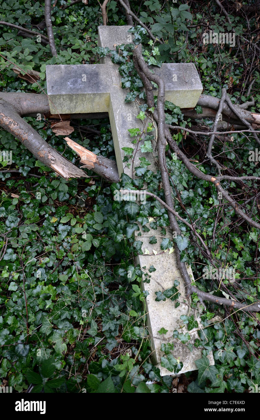 Eine gebrochene Kreuz bewachsen mit Efeu und heruntergefallene Äste in Warriston Friedhof, Edinburgh, Schottland, Großbritannien. Stockfoto