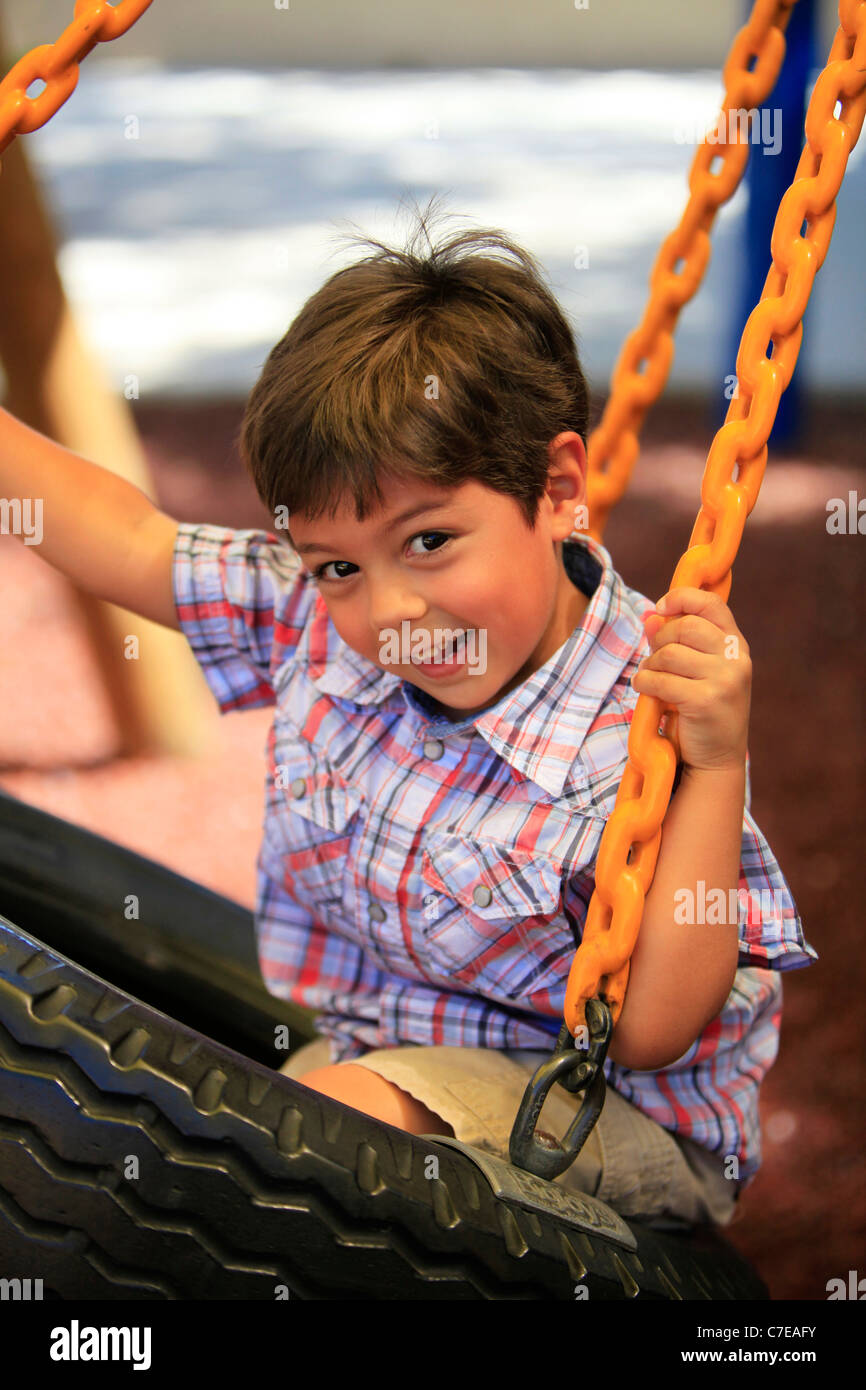 4-jährigen Jungen schwingen auf Reifenschaukel im Spielplatz Stockfoto