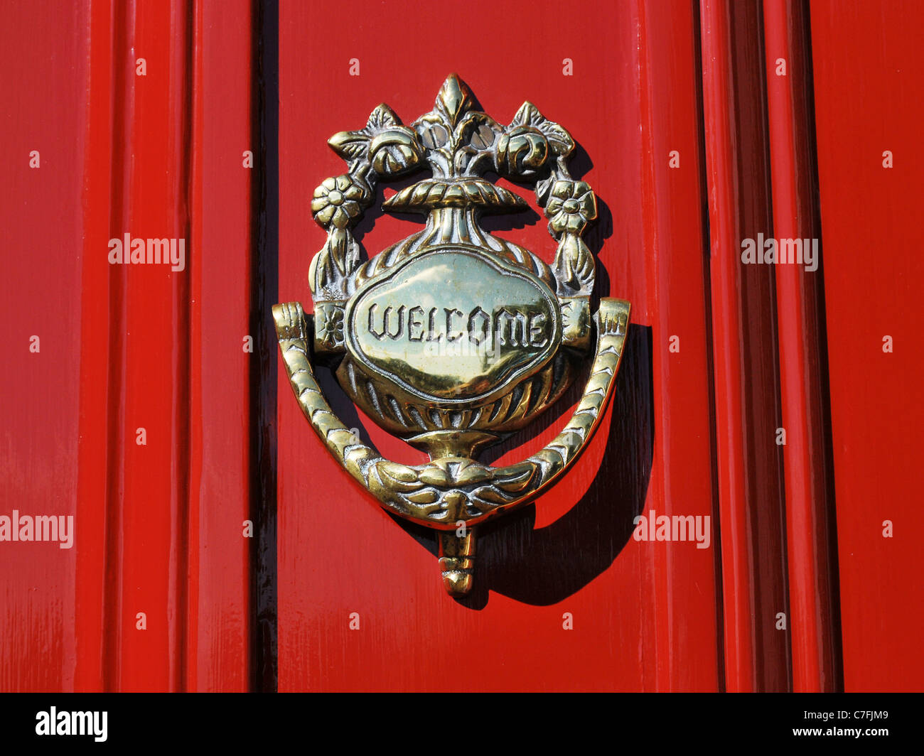 Ein Messing willkommen Klopfer auf eine rote Tür Stockfoto