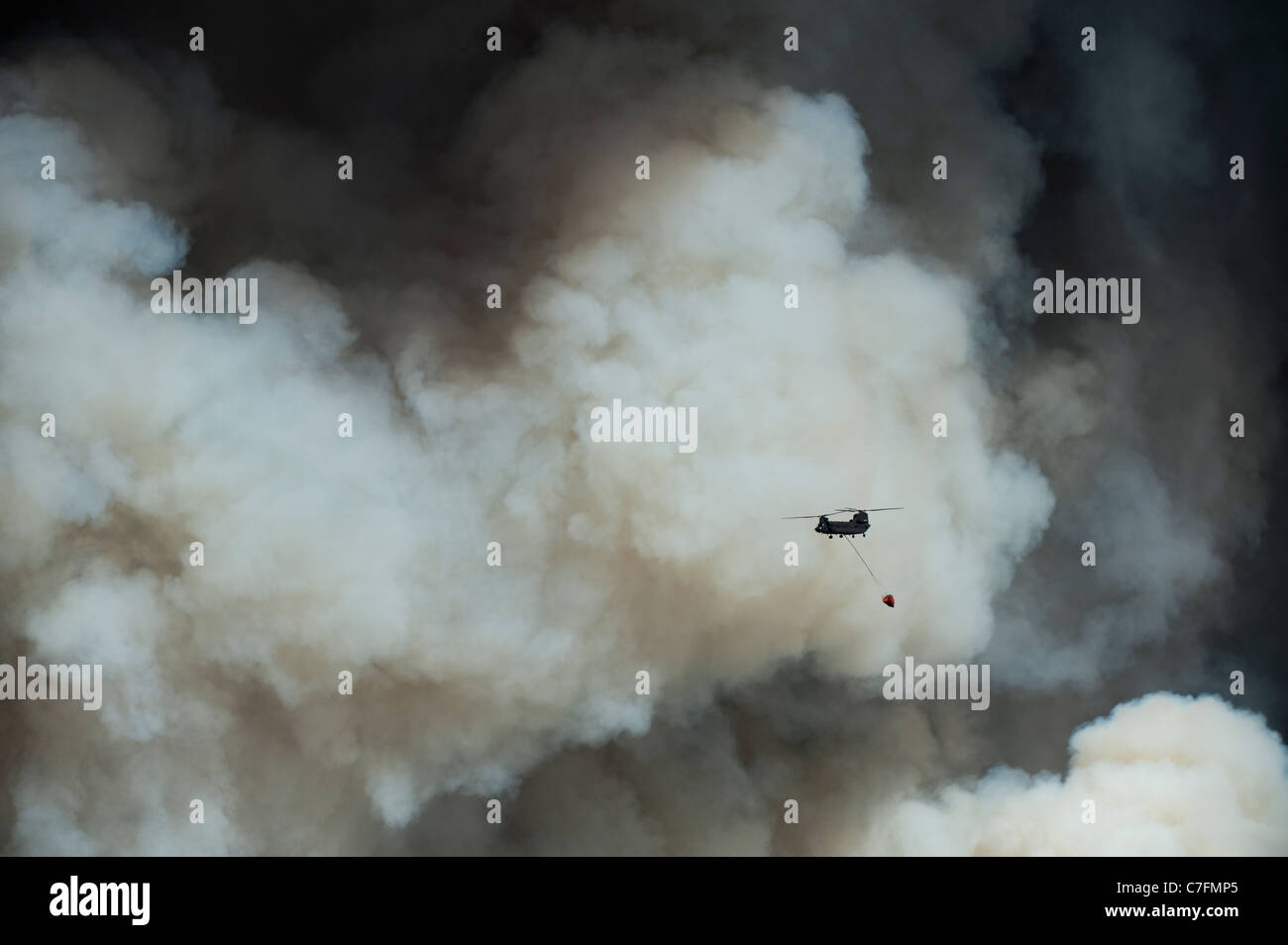 Ein Hubschrauber versucht ein Wassertropfen im Wald östlich von Bastrop, Texas, als wogende Rauch überragt. Stockfoto