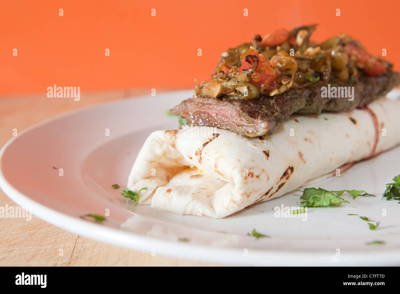 Hausgemachte venezolanischen Stil Burrito erstickt mit marinierten Rock Steak und Feuer gebratene rote Tomaten und grünem Chili. Stockfoto