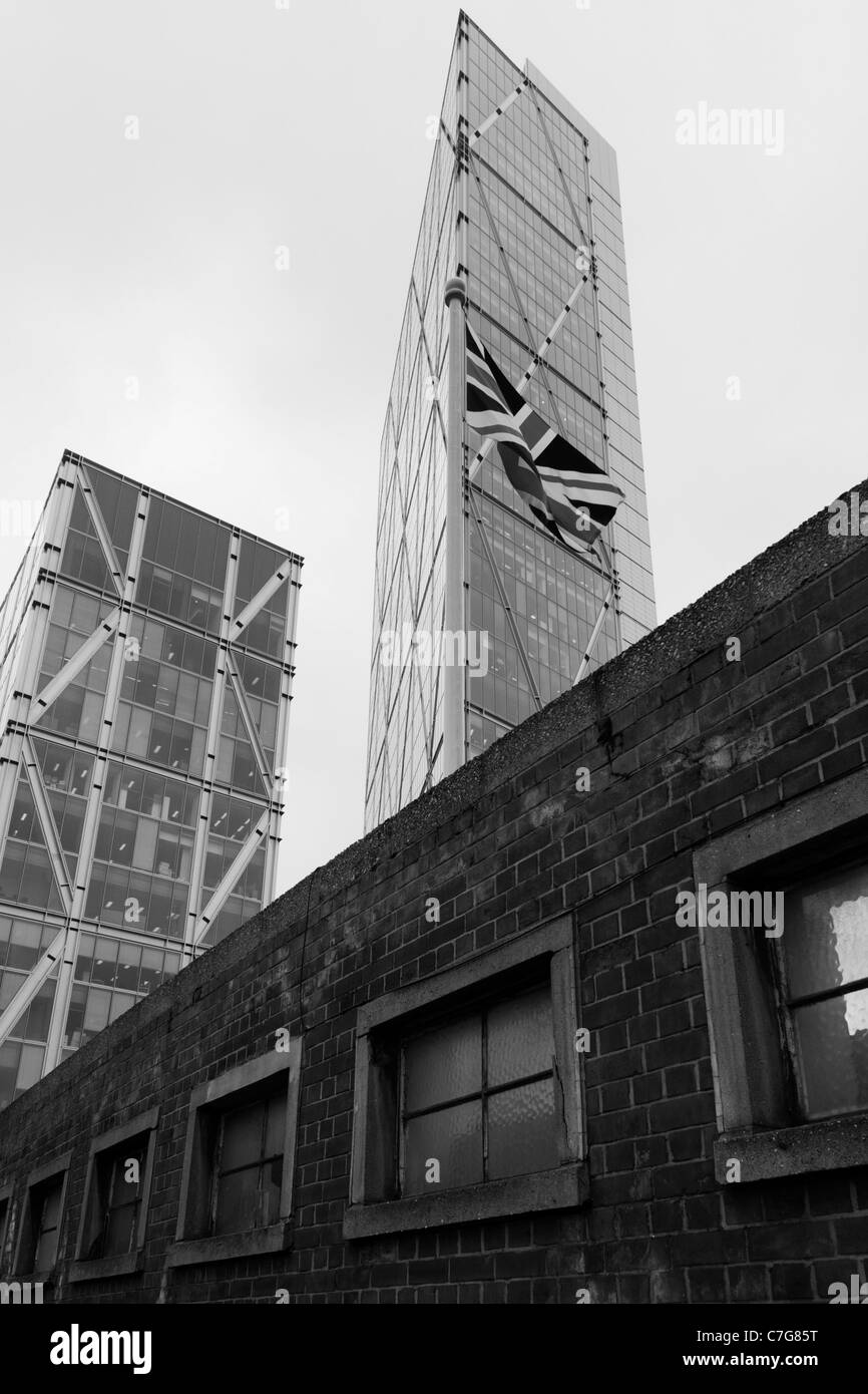 Moderne Wolkenkratzer über eine industrielle Ziegelmauer, Reste einer früheren Ära der Gebäude mit Glas und Stahl gebildet. Stockfoto