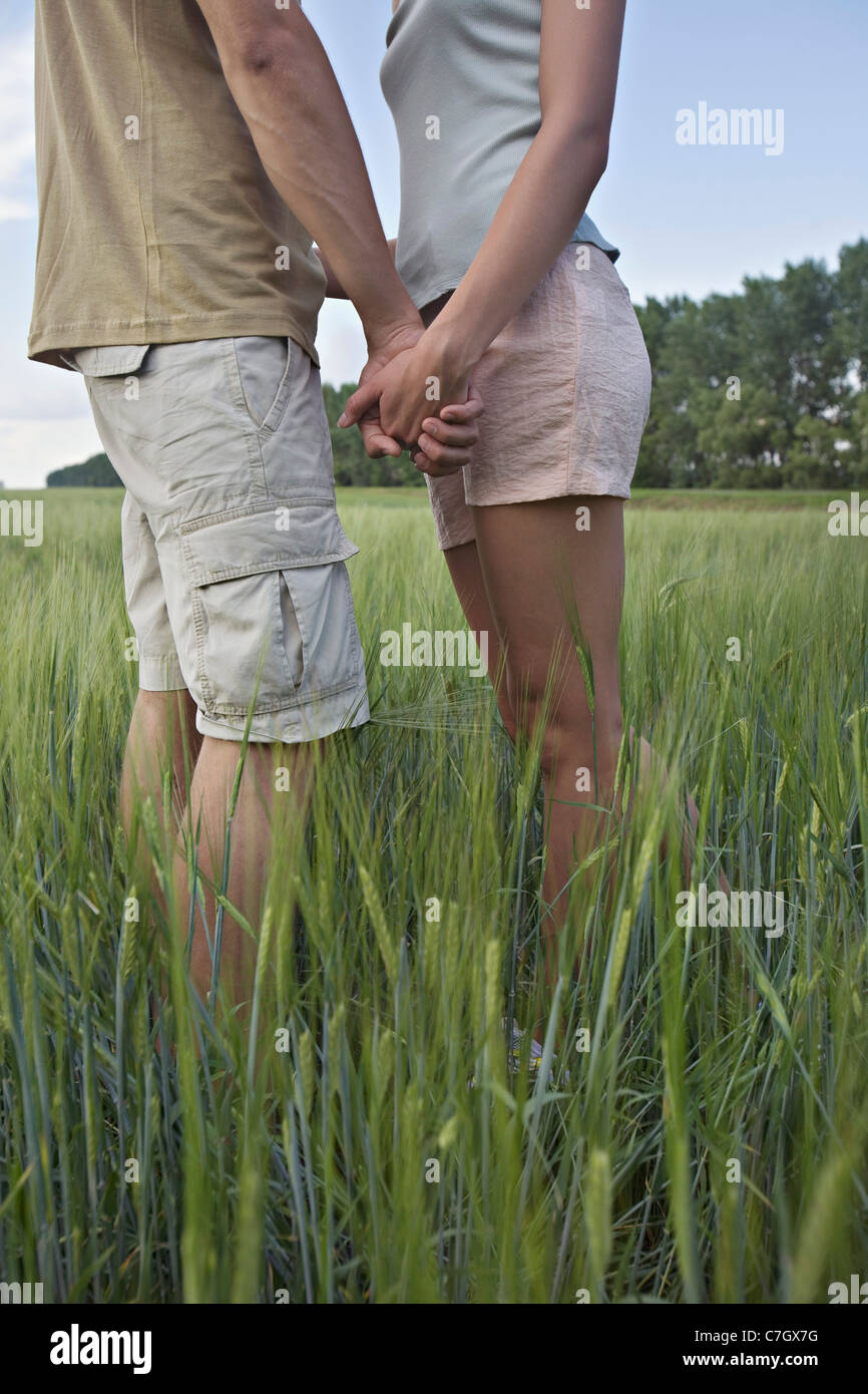 Ein junges Paar halten Hände, stehend in einem Feld Stockfoto